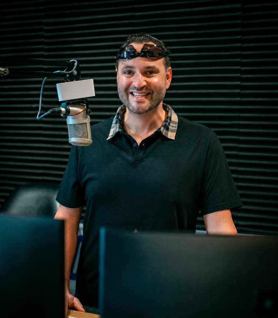 In-game host Rob Daniels smiling in a radio broadcast studio with microphone