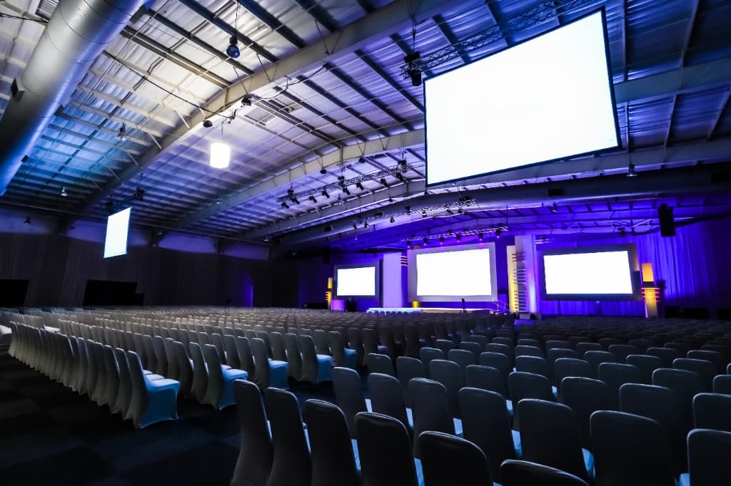 Large conference hall with stage and screens, professional keynote speaking venue